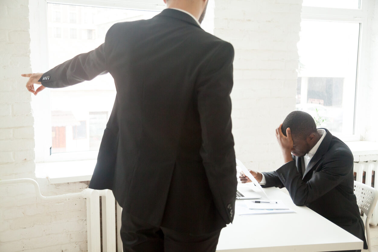 Black employee holding dismissal notice, feeling upset, down. Racial discrimination, termination.